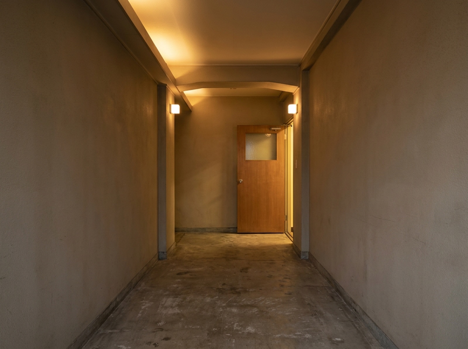 無人の廊下。突き当たりの木の扉が少し開いて、中の明かりが漏れている